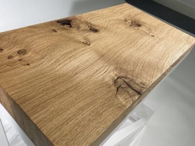 Close-up of a solid oak tabletop showing natural grain and knots by Fuscina