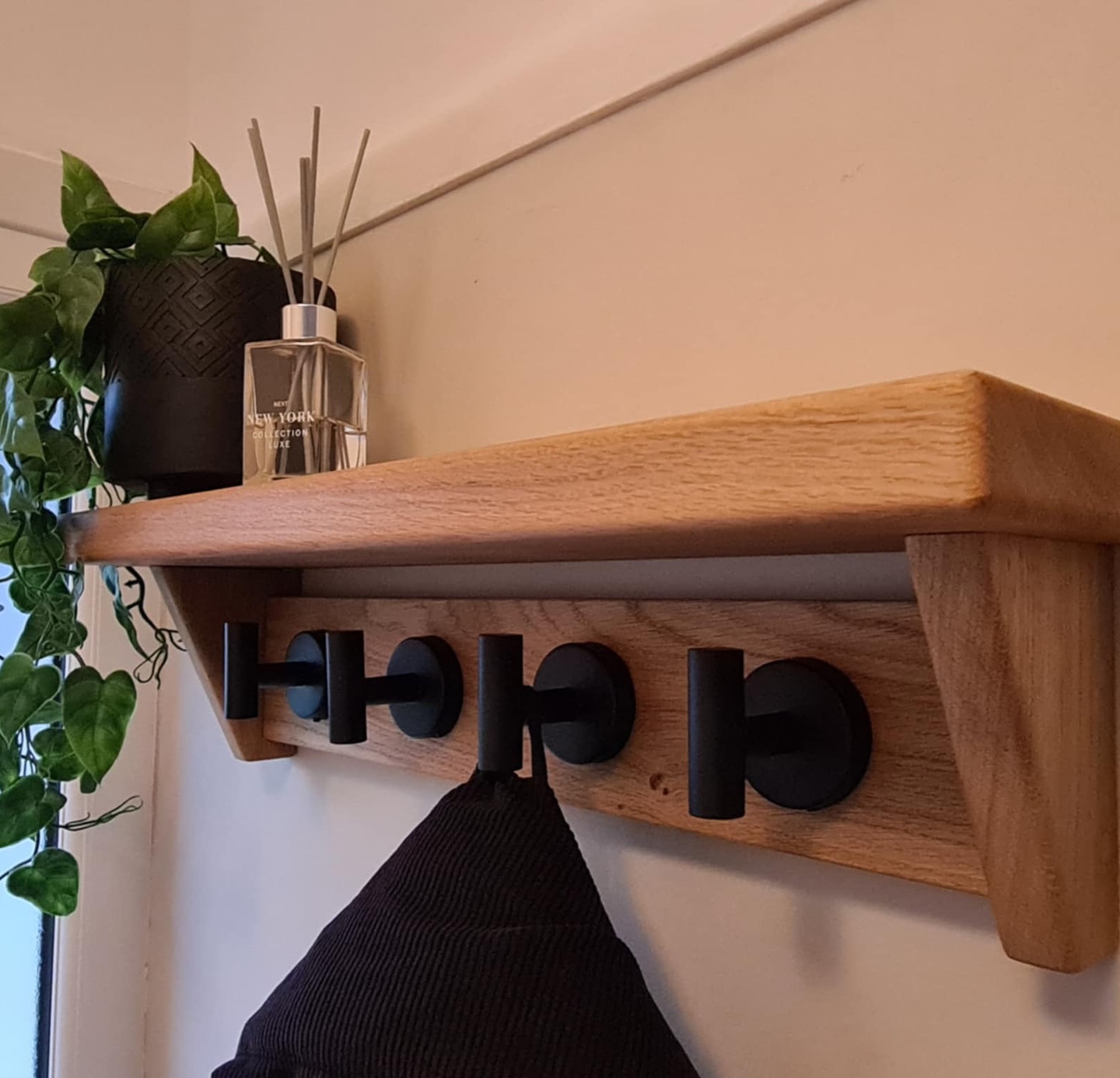 Close-up of a bespoke Fuscina oak coat rack with circular steel hooks