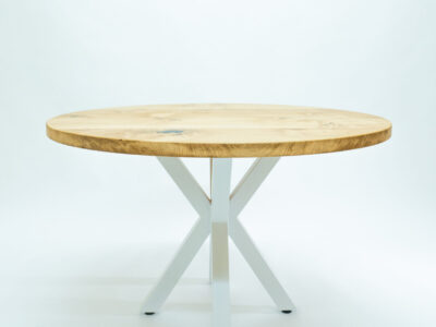 Round oak coffee table with white steel legs from the front at an angle