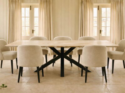 Large dining table with a marble top and black steel X-frame legs surrounded by upholstered chairs