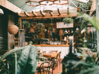 Botanical café interior with hanging plants, rattan pendant lights and rustic wooden bistro tables