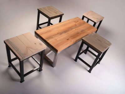 Industrial coffee table with reclaimed wood top and steel frame, surrounded by four matching wooden stools in varied finishes