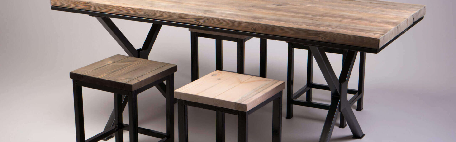 Industrial dining table with reclaimed wood top and black steel X-frame legs, with two matching wooden stools