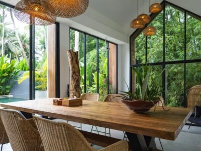 Tropical open-plan dining room with rustic wooden table, rattan chairs and jungle views